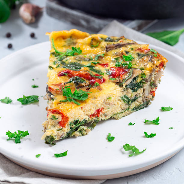 Piece of brunch egg frittata with vegetables on plate, square format
