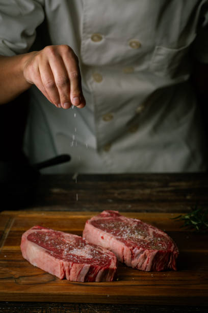istock chef seasoning steak with salt and pepper 2033947344