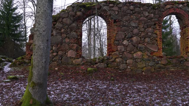 Forgotten church boulder wall remains in gloomy countryside forest environment