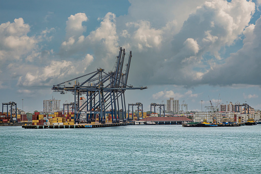 Limon Bay, Colon, Panama - July 24, 2023: Container terminal under blue thick cloudscape. Colon cityscape in back.