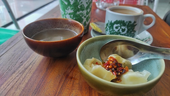 Iced milky tea, butter coffee, and dumplings with chilli souce and broth served on the wooden table