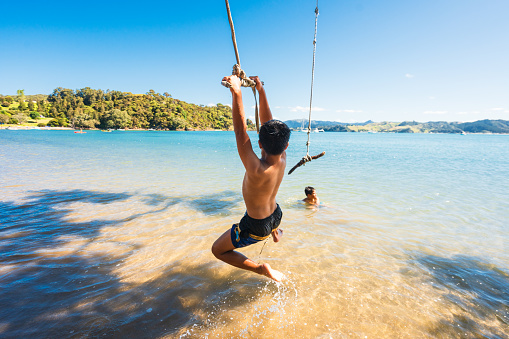 Kids having fun outdoor, enjoying a day at Puriri Bay, Whangaruru North Head, Bay of Islands, Northland New Zealand.