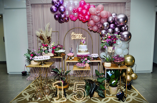 Beautiful table decorated for 15th birthday with flowers, lights and sweets