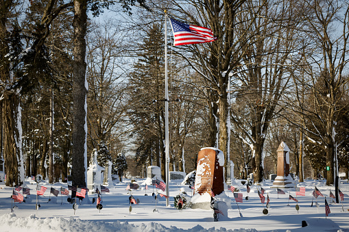Manitowoc, Wisconsin, USA - January 14, 2024: American flags at Evergreen Cemetery with fresh snowfall.