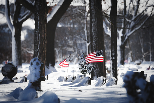 Manitowoc, Wisconsin, USA - January 14, 2024: American flags at Evergreen Cemetery with fresh snowfall.