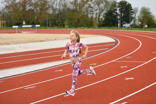 Girl in pink sneakers runs in the stadium