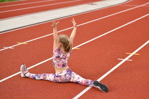 Girl in a pink legging doing splits at the stadium