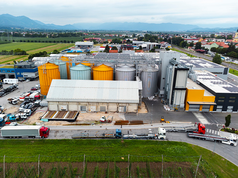 Aerial view of an industrial facility with colorful storage silos, trucks, and surrounding infrastructure.