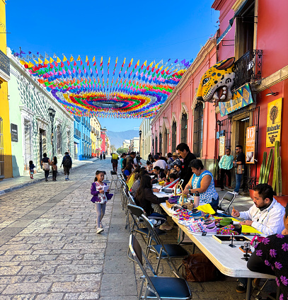 Oaxaca, Mexico: Folk artists at work on a colorful street in downtown Oaxaca; the street is decorated with papel picado—the Mexican art of cut paper.