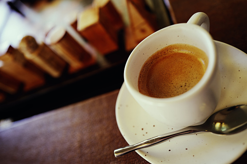 white cup of coffee on a table and in a studio with some coffee pots