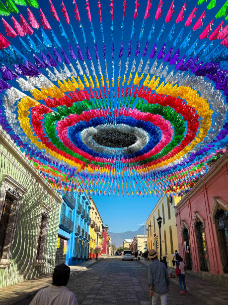Oaxaca, Mexico: Pedestrians walk on a colorful street in downtown Oaxaca decorated with papel picado—the Mexican art of cut paper.