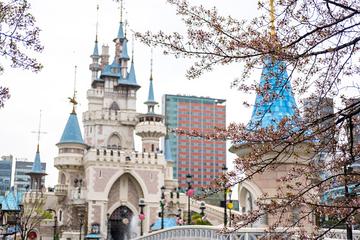 Seoul, South Korea - 4 April 2023: The castle in Magic Land, an outdoor amusement park of Lotte World with cherry blossom on the foreground