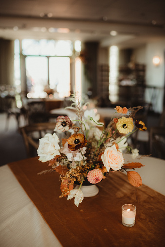 Autumn colored flowers and table runner at wedding reception