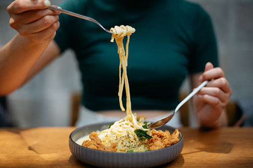 Close up shot of a woman eating creamy salted egg pasta