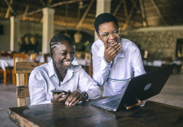 Des étudiantes heureuses utilisant un ordinateur portable tout en apprenant en ligne - Photo