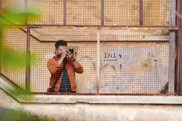 Hip young man with vintage look sits on stone steps with retro cassette player in urban setting, exuding sense of retro fashion and contemplation.