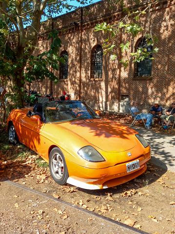 Remedios de Escalada, Argentina - Feb 11, 2024: Old orange sport 1995 Fiat Barchetta roadster convertible at a classic car show in a park. Sunny day