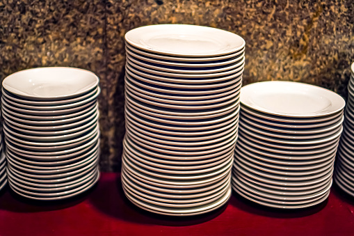 Side view of a set of white dining plates stacked on a dining table.