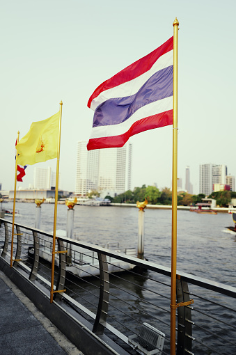 Along the banks of the Chao Phraya River lies one of Bangkok's busiest commercial districts, where the Thai national flag gently flutters in the breeze. Skyscrapers and bustling streets form a unique urban landscape, while the Thai flag symbolizes the pride and glory of the nation. Captured with the Leica Q3.
