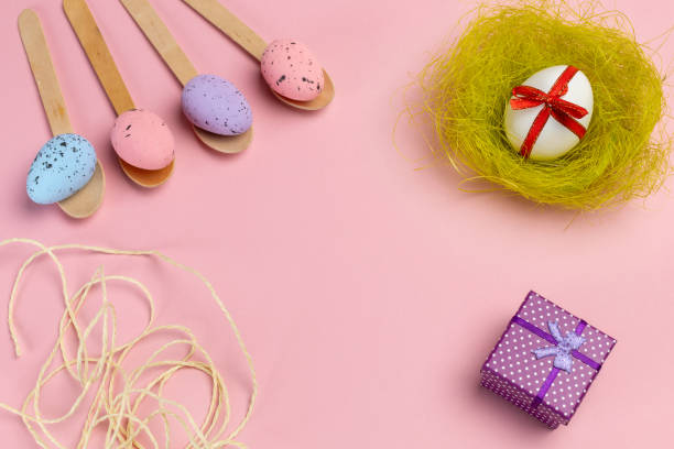 istock Colored Easter eggs on wooden spoons with a nest and a gift box. 2034582566