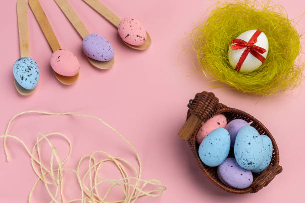 istock Colored Easter eggs on wooden spoons and in a wicker basket with a nest. 2034583090