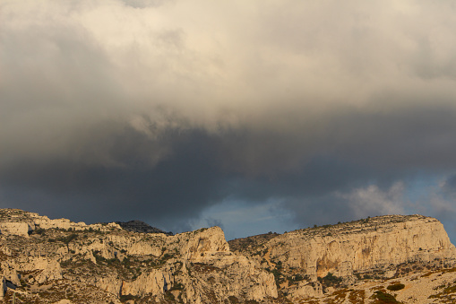 Stormy sky in the famous Calanques of Les Goudes, Marseille, France. Beautiful golden limestone cliffs. Eveneing light.