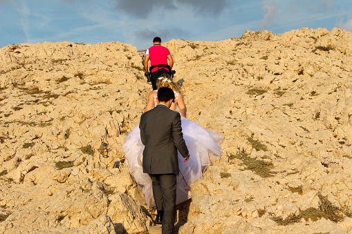 Marseille, France, 09 25 2023 : Photography session of a young couple, newly married, walking in the Calanques of Marseille, Les Goudes, France. Wedding in nature. Wedding dress. Climbing.