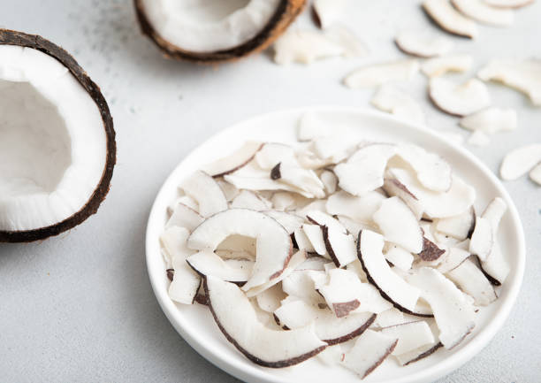 istock Plate with dried organic coconut slices chips and whole ripe coconut on light background.Macro. 2034602270
