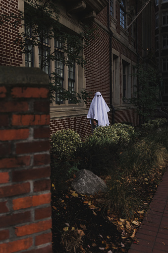 Halloween theme: a spooky and silly ghost wearing sunglasses is haunting outside a very old brick building in Downtown Portland. Halloween humor and spooky theme.