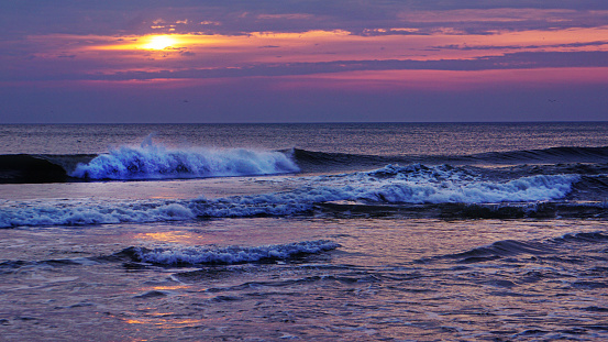 A scenic sunrise seascape view of waves along the the shore of the Outer Banks in Nags Head, North Carolina.