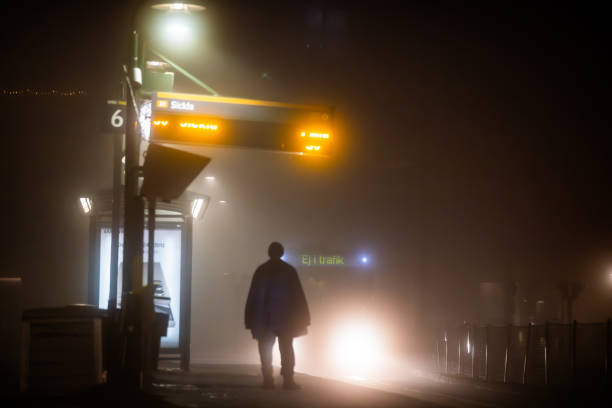 Stockholm, Sweden Jan 30, 2024 A person at a tram stop in the night fog in the Liljeholmen district.