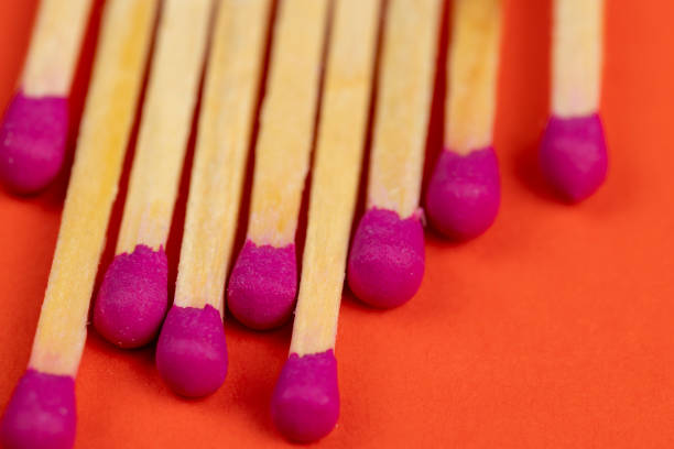 long wooden matches on a paper background, matches with a red pink substance for lighting on an orange background