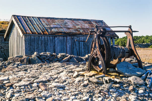 해안의 나무 헛간 옆에있는 오래 된 보트 윈치 - boathouse work tool equipment old 뉴스 사진 이미지