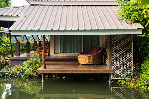 Sofa bed on patio by canel of luxury resort with skyline reflection in morning. Holiday maker and vacation in Thailand.