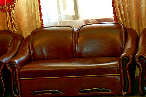 a long upholstered seat with a back and arms, for two or more people