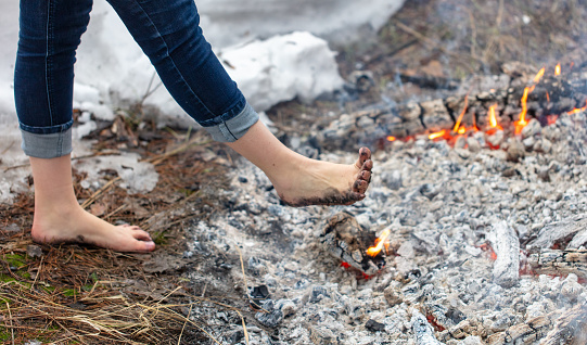 Legs of a girl walking on burning coals.