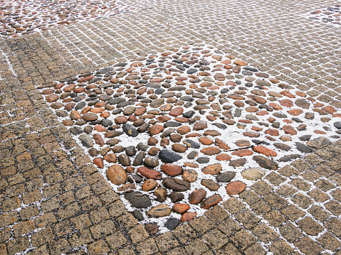 A view of a traditional cobblestone pavement in Gothenburg, lightly covered by snow. The winter seasons effect is visible as snow outlines the stones, creating a textured pattern that highlights the historical charm of the citys walkways.