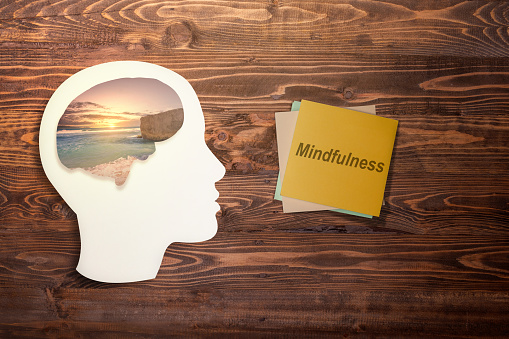 Stack of paper with mindfulness text and a brain with a nature view in the human head on the table. Health mindfulness concept