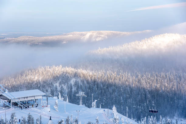 Warm lights illuminate ski slopes among forest covered with snow at dusk, Ruka, Kuusamo, Finland