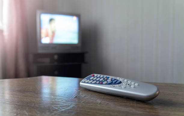istock Old remote control in wooden table beside television set in retro style 2034828686