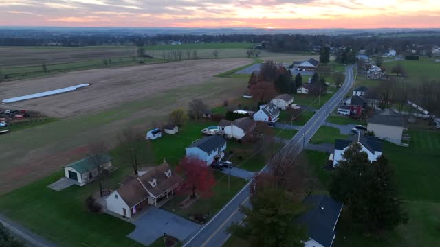 Rural Pennsylvania during late autumn and winter sunset. Aerial tracking shot above houses with farmland.