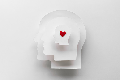 Human head shapes in paper cut style. While the red heart symbolizes unity and love, the relationship among the stacked heads represents connection, loyalty, and emotional closeness.