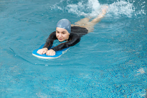 Woman who just learned to swim swims with Swimming Float in a swimming pool