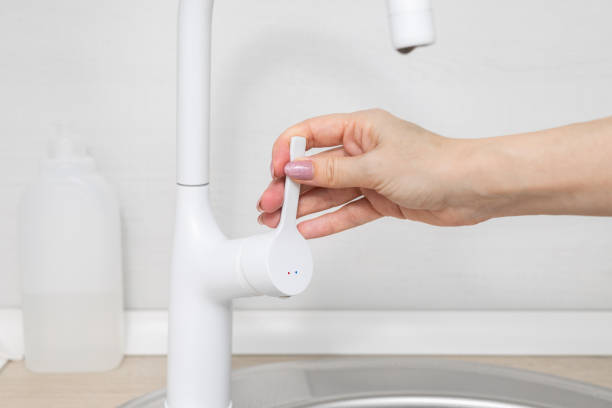 istock man opens the water tap in the kitchen. 2034895944