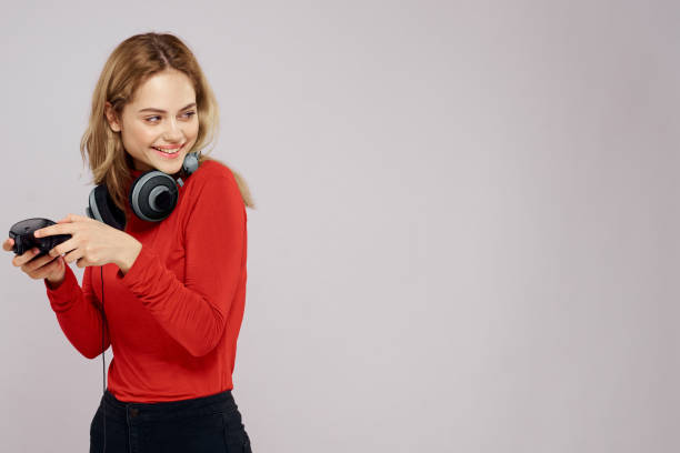 istock Woman with headphones controller in hands a console game fun leisure red jacket lifestyle light background 2034917687