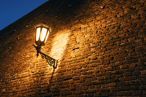 In the dark of night, the flickering light of antique lanterns against the weathered brick walls of fortress creates an enchanting scene of old-world charm.