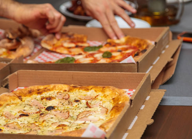 istock several pizzas in cardboard boxes are sitting on a table 2034937603