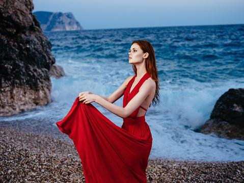 woman in red dress on the beach ocean posing luxury romance. High quality photo