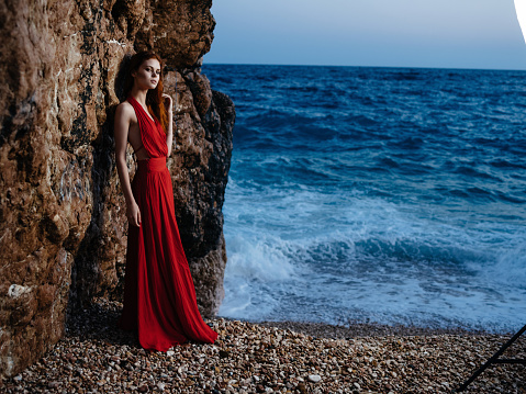 woman in red dress on the beach ocean posing luxury romance. High quality photo