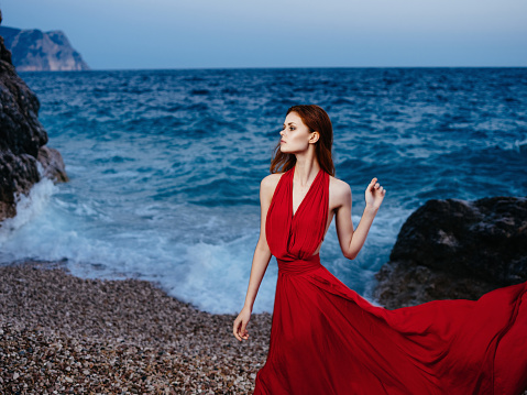 pretty woman in red dress posing near cliff beach vacation romance. High quality photo